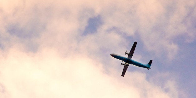 Open propellor plane flying among pink sunset clouds with the sun shining on the body. Great shot to denote travel and vacations.