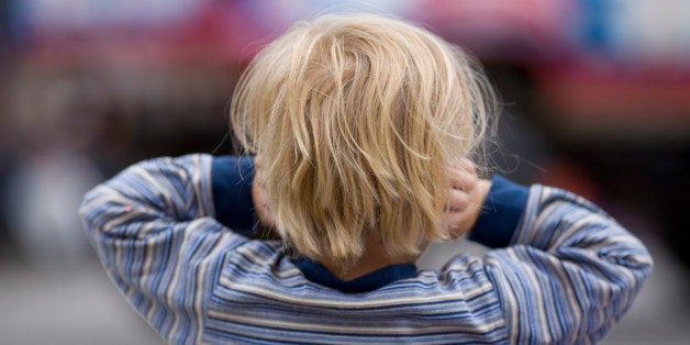 A little boy holds his ears.