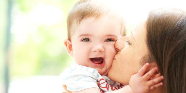 Mother kissing smiling boy toddler on the cheek