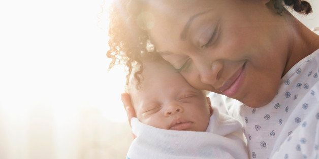 Mixed race mother cradling newborn baby