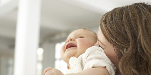 Mother kissing her laughing baby girl