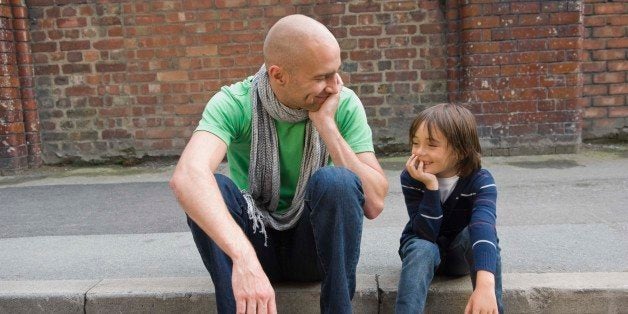 Father and son sitting on curb