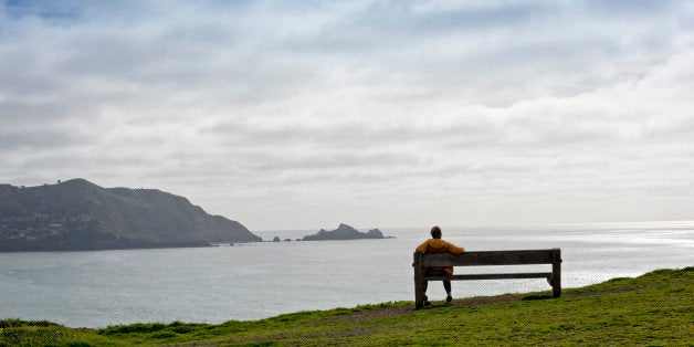 Woman sitting on a wooden bench overlooking Pacific Ocean