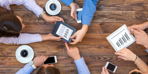 Top View of Arms of Group Young Business People Discussing Data on Electronic Gadgets Passing Coffee Mug Pointing on something