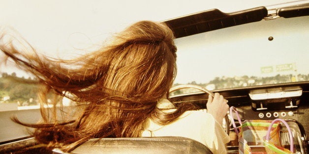 Woman driving convertible car, rear view