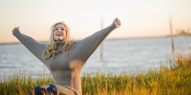 Portrait of stylish young woman in grey sweater posing along grassy coast