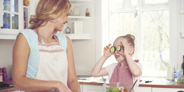 Cute little girl playfully holding cucumber slices over her eyes