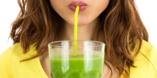 Close up of woman drinking green smoothie. Isolated on white background.