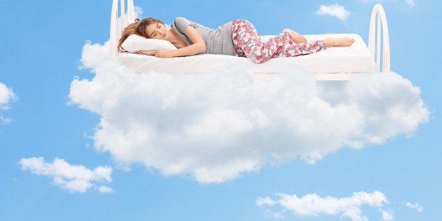 Relaxed young woman sleeping on a comfortable bed in the clouds