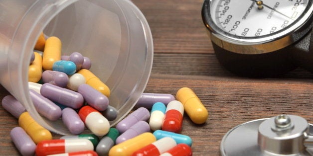 Medical Devices Monometer, Pulsometer, Stethoscope and Scattered From Vial Colorful Pills, Drugs and Capsules on Brown Wooden Table