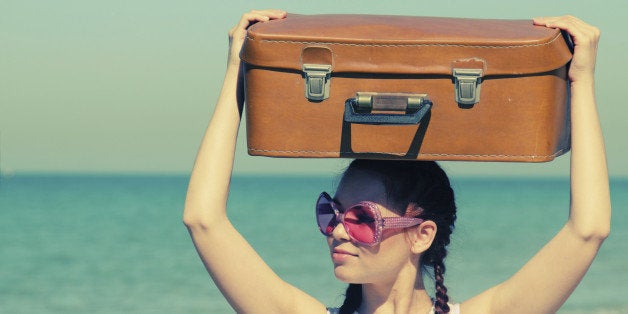 woman with suitcase on the beach. Photo in old image style.