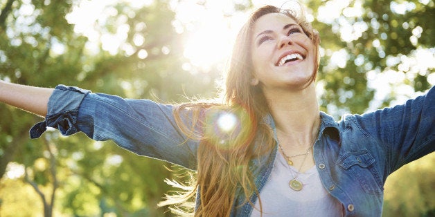 A shot of a young woman standing outdoors with her arms outstretched