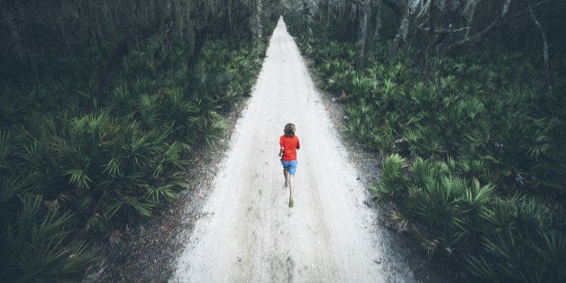 A solitary male runner out for a training run on rural road at sunset on Cumberland Island off the coast of Georgia.