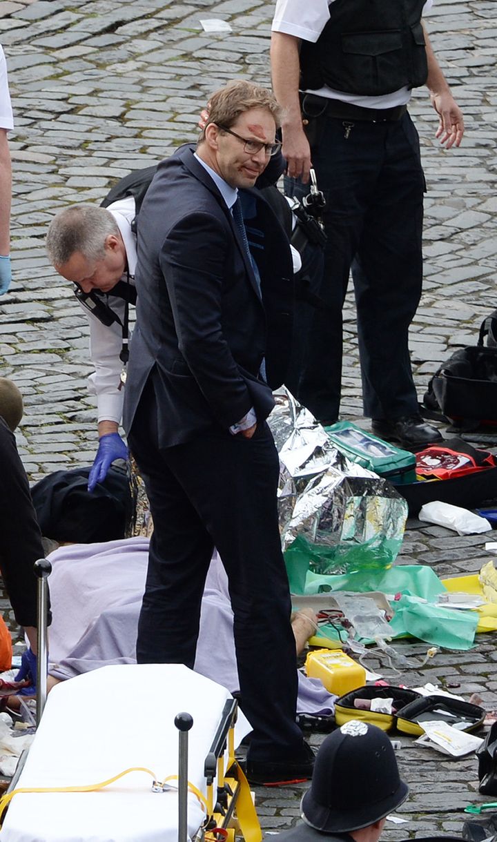 MP Tobias Ellwood stands amongst the emergency services at the scene outside the Palace of Westminster, London