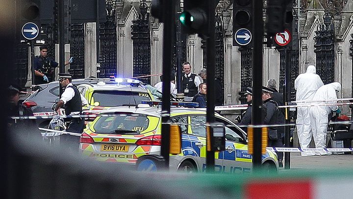 Armed police officers stand guard, as forensics officers work around the vehicle Khalid Masood crashed into the railings outside the Palace of Westminster