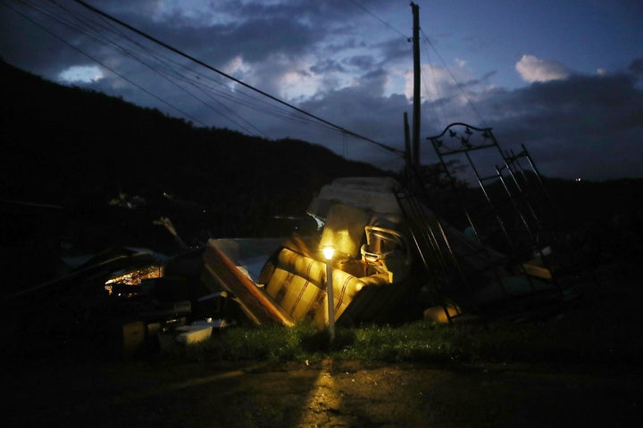 A donated solar lamp in a driveway illuminates storm debris still waiting to be collected on Dec. 25, 2017, in Morovis, Puerto Rico.