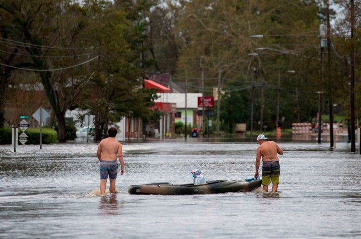 Two men use a kayak to carry supplies across a road flooded by Hurricane Florence in Pollocksville, North Carolina, on September 16, 2018