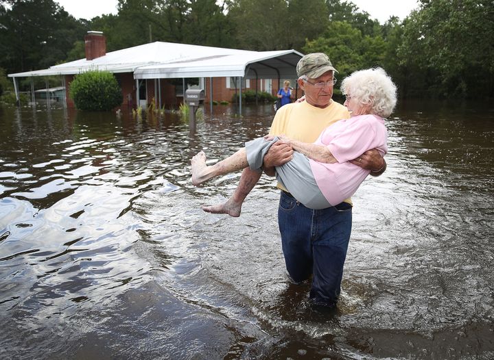 Bob Richling carries Iris Darden as water from the Little River starts to seep into her home on Monday in Spring Lake, North Carolina.