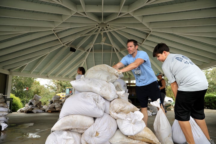 A Boy Scout volunteer and his father help stack sandbags donated by the city of Greenville.