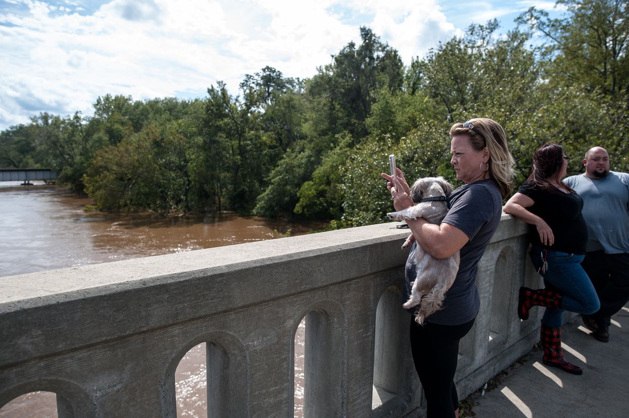 Laura Walters of Fayetteville holds her dog Abby as she takes a photo of the Cape Fear River on Monday.