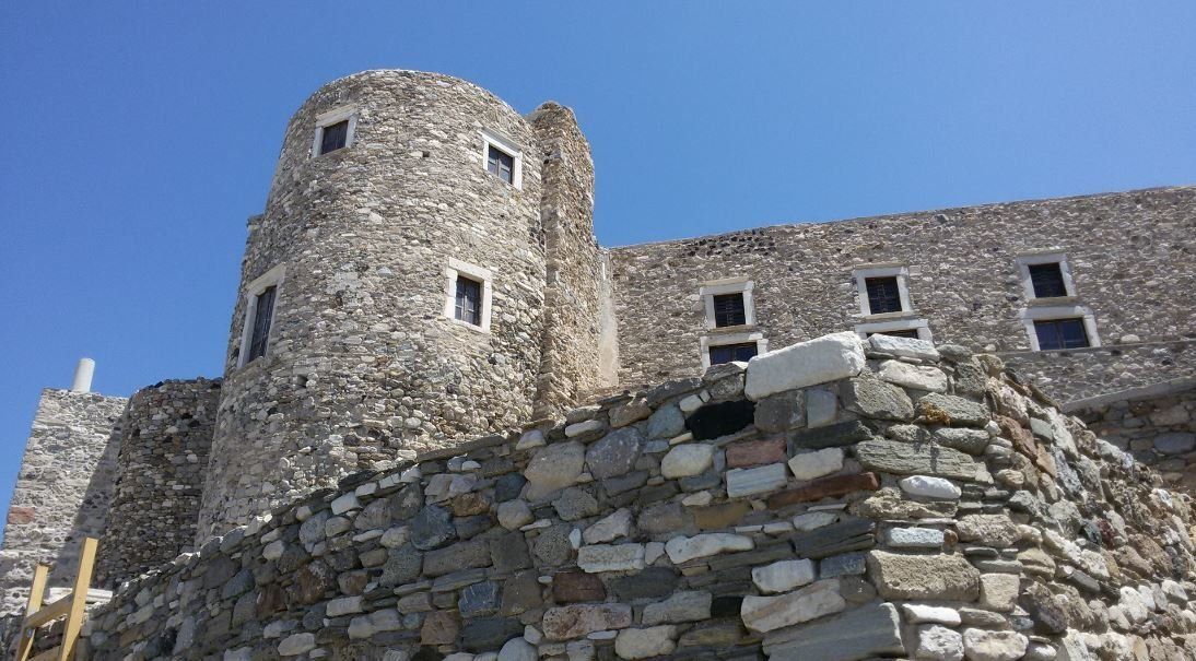 Το Κάστρο της Χώρας της Νάξου με την γυμνή λιθοδομή. Άποψη από την είσοδο του Κάστρου (Τρανή Πόρτα) και προς τον Πύργο των Κρίσπι – Γλέζου ο οποίος στεγάζει το Βυζαντινό Μουσείο της Νάξου και είναι ο μοναδικός από του 12 πύργους του Κάστρου που σώζεται σήμερα