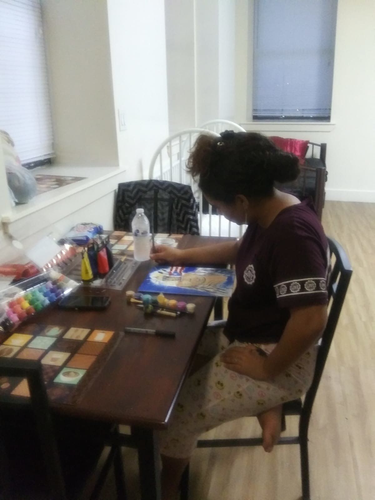 Jennyfer's daughter, 14, painting at the table in their room at the Bronx shelter 