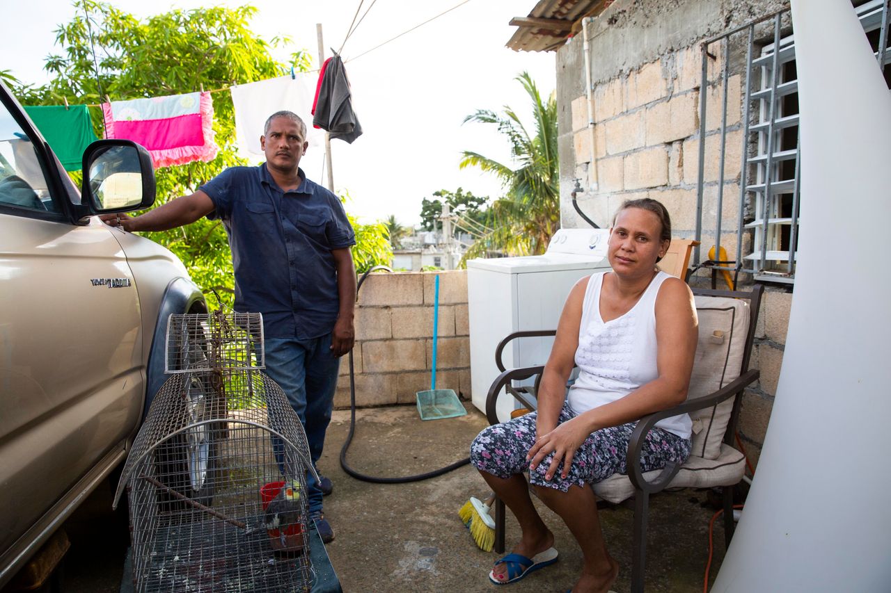 In August, Guerrero Herrera and his wife, Daysi Lantigua, sit on the front porch of their new cement home, which is just up the road from the wooden house they lost.