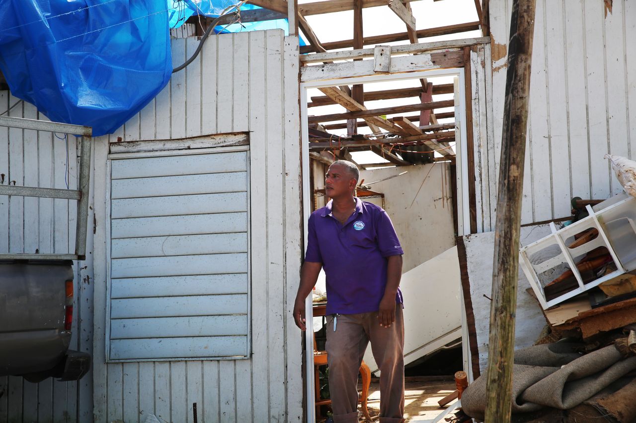 Three weeks after the storm, Danny Guerrero Herrera stands at the door of his home, which was largely destroyed by Hurricane Maria.