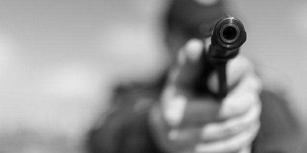 Detail of a police officer holding gun. Selective focus with shallow depth of field. Black and white toning.