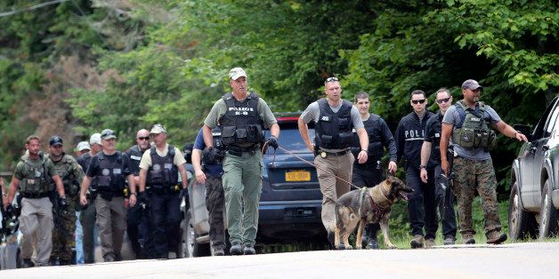 Law enforcement officers walk along a road as the search continues for two escaped prisoners from the Clinton Correctional Facility in Dannemora, on Monday, June 22, 2015, in Owls Head, N.Y. In the more than two weeks since inmates David Sweat and Richard Matt escaped, more than 800 law enforcement officers have gone door-to-door checking houses, wooded areas, campgrounds and summer homes. (AP Photo/Mike Groll)