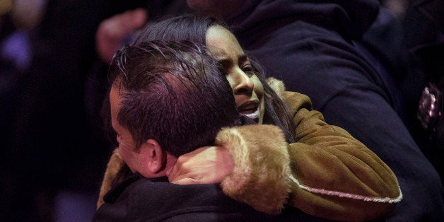 ADDS BOTH OFFICERS KILLED - Mourners gather before the bodies of two fallen NYPD police officers are transported from Woodhull Medical Center, Saturday, Dec. 20, 2014, in New York. An armed man walked up to two New York Police Department officers sitting inside a patrol car and opened fire Saturday afternoon, killing both officers before running into a nearby subway station and committing suicide, police said. (AP Photo/John Minchillo)