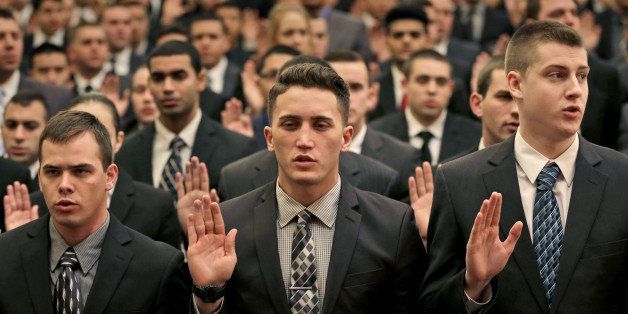 New York Police Department recruits take an oath during an NYPD swearing-in ceremony in New York, Wednesday, Jan. 7, 2015. Mayor Bill de Blasio was speaking to hundreds of new police hires who will be spending the next six months in police academy before becoming police officers.(AP Photo/Seth Wenig)