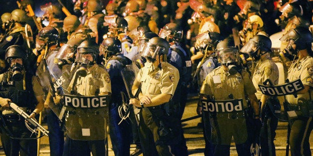 FERGUSON, MO - AUGUST 17: Police advance on demonstrators protesting the killing of teenager Michael Brown on August 17, 2014 in Ferguson, Missouri. Police shot smoke and tear gas into the crowd of several hundred as they advanced near the police command center which has been set up in a shopping mall parking lot. Brown was shot and killed by a Ferguson police officer on August 9. Despite the Brown family's continued call for peaceful demonstrations, violent protests have erupted nearly every night in Ferguson since his death. (Photo by Scott Olson/Getty Images)