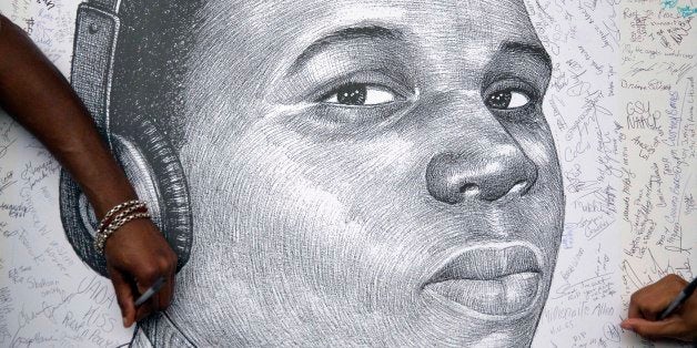 FILE - In a Monday, Aug. 18, 2014 file photo, protestors autograph a sketch of Michael Brown during a protest, in Atlanta. Mi