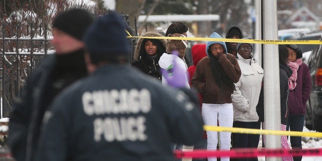 CHICAGO, IL - DECEMBER 15: Neighborhood residents watch as police investigate a homicide scene after a 24-year-old man was f