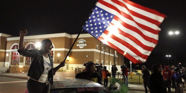 Gina Gowdy joins protesters on the street outside a Ferguson, Mo., fire station, Wednesday, March 4, 2015, in Ferguson. The Justice Department on Wednesday cleared a white former Ferguson police officer in the fatal shooting of an unarmed black 18-year-old, but also issued a scathing report calling for sweeping changes in city law enforcement practices it called discriminatory and unconstitutional. (AP Photo/Charles Rex Arbogast)