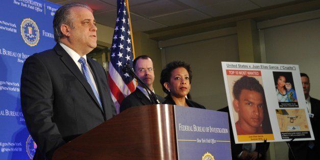 FBI Assistant Director-in-Charge George Venizelos (L) and US Attorney for the Eastern District of New York Loretta Lynch (C) announce that Juan Elias Garcia (R, on poster), also known as 'Cruzito', from El Salvador, has been added to FBIs Ten Most Wanted Fugitives March 26, 2014 in New York. Garcia is wanted for the murder of 19-year-old Vanessa Argueta and her 2-year-old son Diego Torres in Central Islip, New York on February 5, 2010. AFP PHOTO/Stan HONDA (Photo credit should read STAN HONDA/AFP/Getty Images)