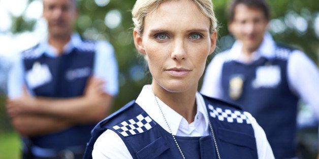 Shot of a serious policewoman with her colleagues in the background