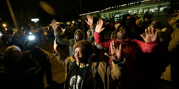 Barbara Jones joined by other protesters raise their hands up in the air as they protest Monday, Nov. 24, 2014, in Ferguson, Mo., more than three months after an unarmed black 18-year-old man was shot and killed there by a white policeman in Ferguson. Ferguson and the St. Louis region are on edge in anticipation of the announcement by a grand jury whether to criminally charge Officer Darren Wilson in the killing of 18-year-old Michael Brown. (AP Photo/Charlie Riedel)