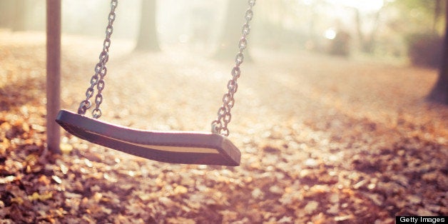 Moving playground swing in last sun light in autumn.