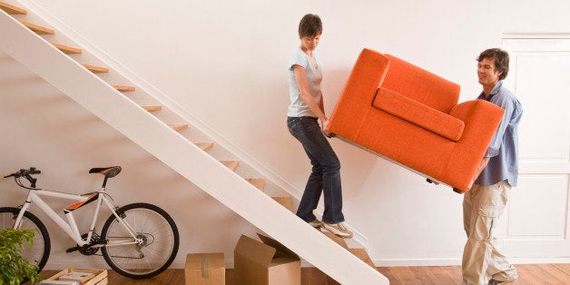 Couple carrying armchair up stairs