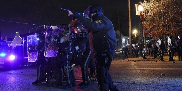 Police points his rifle at demonstrators after a grand jury decided a white policeman will not face charges for killing a bla