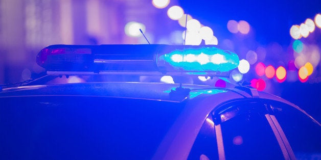 Blue light flasher atop of a police car. City lights on the background. 