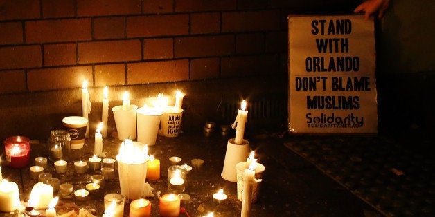 SYDNEY, AUSTRALIA - JUNE 13: A woman places a banner next to the candles during a candlelight vigil for the victims of the Pulse Nightclub shooting in Orlando, Florida, at Newtown Neighbourhood Centre on June 13, 2016 in Sydney, Australia. 50 people were killed and 53 injured after a gunman opened fire on people in a gay nightclub in Florida. It is the deadliest mass shooting in US history. (Photo by Daniel Munoz/Getty Images)