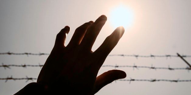 Silhouette hand extending to the sky with barbwire and sunlight , vintage tone