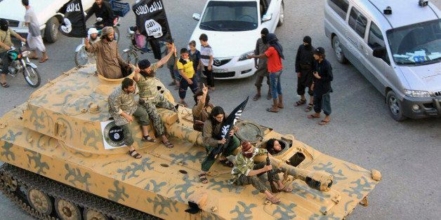 This undated image posted by the Raqqa Media Center, a Syrian opposition group, on Monday, June. 30, 2014, which has been verified and is consistent with other AP reporting, shows fighters from the al-Qaida linked Islamic State of Iraq and the Levant (ISIL) sitting on their tank during a parade in Raqqa, Syria. Militants from an al-Qaida splinter group held a military parade in their stronghold in northeastern Syria, displaying U.S.-made Humvees, heavy machine guns, and missiles captured from the Iraqi army for the first time since taking over large parts of the Iraq-Syria border. (AP Photo/Raqqa Media Center)
