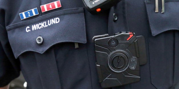 In this Nov. 5, 2014 photo, Sgt. Chris Wicklund of the Burnsville Police Department wears a body camera beneath his microphone. Minneapolis, with the largest police department in Minnesota, has become the latest to equip officers with body cameras in what officials say is an effort to improve transparency and hold police accountable. The goal in Burnsville is to have all uniformed offices equipped with cameras by the end of the year. (AP Photo/Jim Mone)