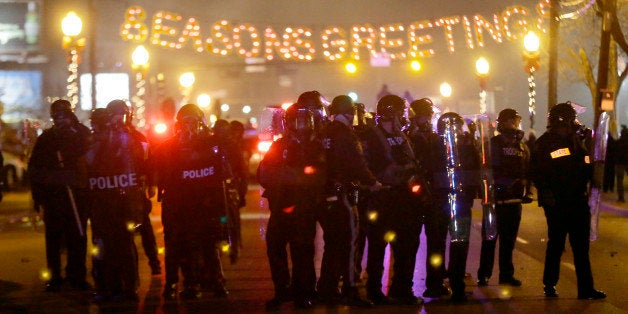 Police gather on the street as protesters react after the announcement of the grand jury decision Monday, Nov. 24, 2014, in Ferguson, Mo. A grand jury has decided not to indict Ferguson police officer Darren Wilson in the death of Michael Brown, the unarmed, black 18-year-old whose fatal shooting sparked sometimes violent protests. (AP Photo/Charlie Riedel)