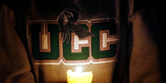 Diana Nicolay, a former employee of Umpqua Community College, wears a school sweatshirt during a candlelight vigil for those