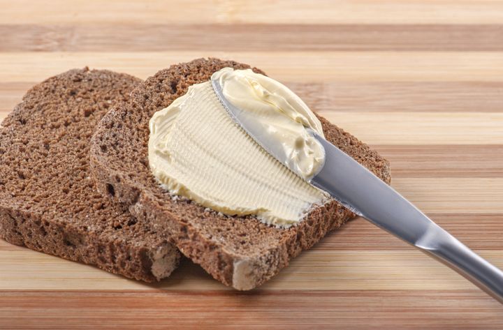 a knife spreading butter on rye ...